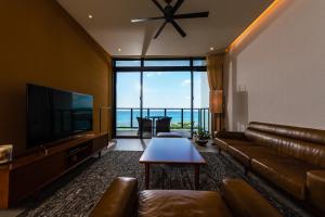 a living room with a couch and a television and a table at Condominium NOOSA in Nago