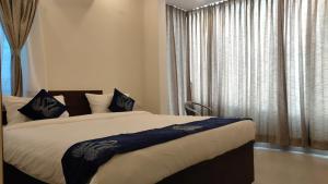 a bedroom with a bed and a window with curtains at AMULYA FINE DINE RESIDENCY in Bangalore