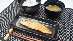 un pezzo di pesce su un piatto su un tavolo con bacchette di Hotel Oarai Seven Seas(Adult Only) a Ōarai