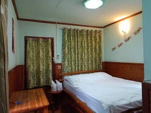 a bedroom with a bed and a table and curtains at เพชร การ์เด้น -Phet Garden Resort, Nakhonthai 1 in Nakhon Thai