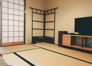 a living room with a flat screen tv and a door at Kyoto Nijo Guest House HoshiIke villa in Kyoto