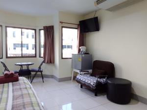 a bedroom with a bed and a tv on the wall at Living Room Guesthouse & Cafe Bar in Karon Beach