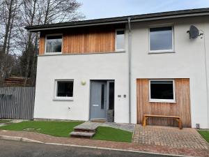 a white house with a wooden door at Woodside retreat holiday home in Aviemore in Aviemore