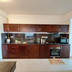 cocina con armarios de madera, fregadero y fogones en Modern apartment in close proximity to the Beach en Colombo