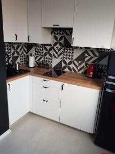 a kitchen with white cabinets and black and white tiles at Apartament Rodzinny in Kłodzko