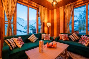Zostel Sissu في Sissu: غرفة معيشة مع أريكة خضراء وطاولة