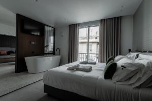 um quarto com uma cama grande e uma banheira em Athinaion Recreation Suites em Atenas