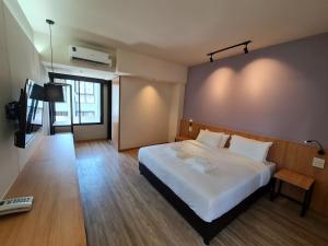 een slaapkamer met een groot wit bed en een televisie bij The Neuf@Ratchada in Bangkok