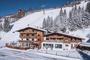 ein Blockhaus im Schnee mit Skilift in der Unterkunft Hotel & Appartements Tiroler Buam in Saalbach-Hinterglemm