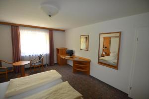 a hotel room with a bed and a desk and a mirror at Alpenhotel Widderstein in Mittelberg