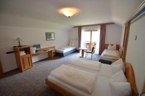 una camera d'albergo con due letti e una scrivania di Alpenhotel Widderstein a Mittelberg