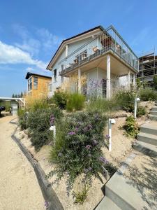 a house on the beach with flowers in front of it at HAUS IM SCHILF 1 - Ferienwohnungen am Hainer See bei Leipzig in Neukieritzsch