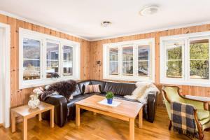 a living room with a leather couch and windows at Flåm Hostel in Flåm