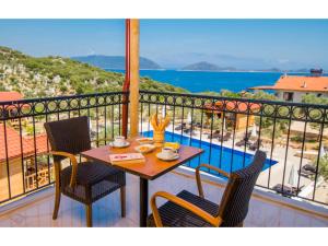 uma mesa e cadeiras numa varanda com vista para o oceano em Doganın Ruhu Hotel & Bungalow em Kas