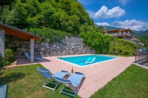 a swimming pool with a table and chairs and a house at Parco dei Cervi Terrazzo in Menaggio