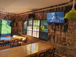 un restaurante con mesas y TV en una pared de ladrillo en พูลวิลล่า เชียงใหม่, en Doi Saket
