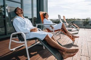 two people sitting in chairs on a balcony at Thermal Hotel Balance Lenti in Lenti