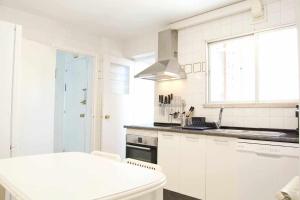 a white kitchen with a sink and a stove at Apartamento AVENIDA DO MAR in A Coruña