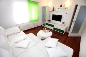 a living room with a white couch and a tv at Apartments Nakir in Slatine