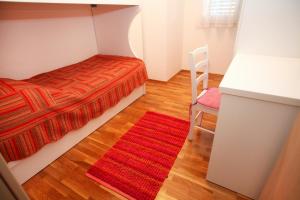 a small bedroom with a bed and a red rug at Apartments Nakir in Slatine