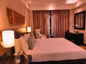 a hotel room with a large bed and a chair at The Raintree, St. Mary’s Road in Chennai