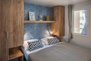1 dormitorio con 1 cama con pared azul en Falkensteiner Premium Mobile Homes and Camping Zadar en Zadar