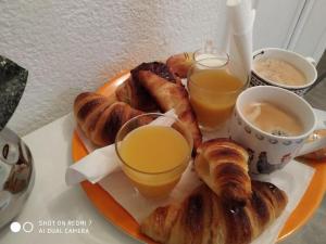 a plate of food with croissants and two glasses of orange juice at CHAMBRES Climatisées Confort,WIFI, GARE TGV,parking,pt dejeuner in Perpignan