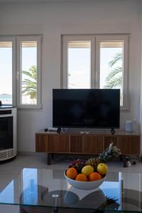 a living room with a television and a bowl of fruit on a table at Fantastic, Front line, Penthouse Apartment with amazing views in Los Urrutias