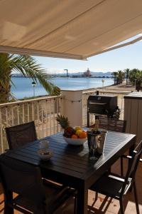a wooden table with a bowl of fruit on a balcony at Fantastic, Front line, Penthouse Apartment with amazing views in Los Urrutias