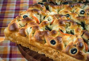 a pizza with black olives and cheese on a table at The Raintree, St. Mary’s Road in Chennai