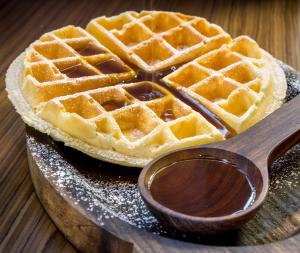 a waffle sitting on a plate with a wooden spoon at The Raintree, St. Mary’s Road in Chennai