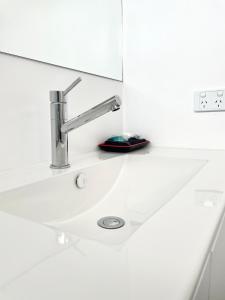 a white bathroom sink with a chrome faucet at Avenue Motel in Ballarat