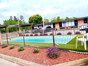 a fence with flowers in front of a swimming pool at Avenue Motel in Ballarat
