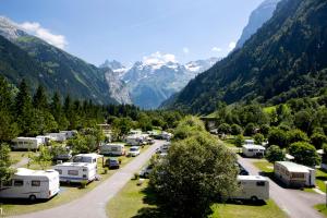 a bunch of rvs parked in a parking lot with mountains at Alpenresort Eienwäldli Camping in Engelberg