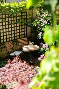 einen Tisch und Stühle in einem Garten mit Blumen in der Unterkunft Boutique Hotel Splendid in München