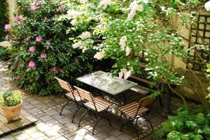 une table et des chaises dans un jardin fleuri dans l'établissement Boutique Hotel Splendid, à Munich