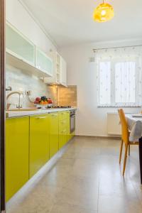 a kitchen with yellow cabinets and a sink and a table at Lovely apartment with city view in Bucharest