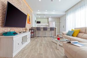un soggiorno con una grande TV a schermo piatto su un muro di mattoni di Genteel Home Castilla Terrace a Siviglia