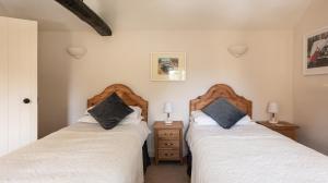 2 Betten in einem Zimmer mit 2 Nachttischen und Lampen in der Unterkunft Camside, Chipping Campden - Taswell Retreats in Chipping Campden