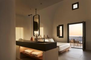 a bathroom with a sink and a bed with a view at Orama Hotel & Spa in Fira