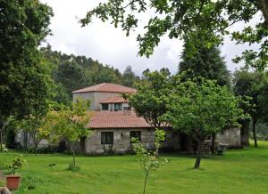 ein altes Steinhaus auf einem Feld mit Bäumen in der Unterkunft A Bouza in Samieira
