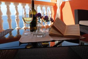 stół z książką, kieliszki do wina i kwiaty w obiekcie Holiday Home Adriatic View w mieście Prižba