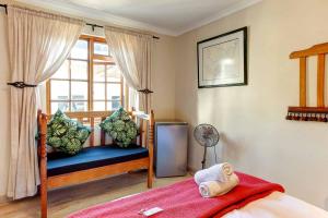 a bedroom with a bed and a window with a fan at Penguin - Double En-Suite Studio in Cape Town