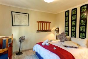 a bedroom with a bed with a fan and windows at Penguin - Double En-Suite Studio in Cape Town +3 photos