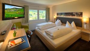 ein Hotelzimmer mit einem Bett und einem Fernseher in der Unterkunft Gasthaus Löwen in Bernau im Schwarzwald