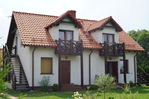 een wit huis met een rood dak bij Mazurska Apartamenty in Rydzewo