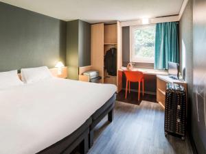 um quarto com uma cama e uma secretária com um computador em ibis Rennes Cesson em Cesson-Sévigné