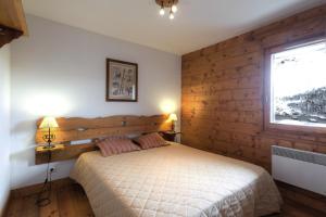 um quarto com uma cama e uma parede de madeira em Belambra Clubs Résidence Les Menuires - Le Hameau Des Airelles em Les Menuires