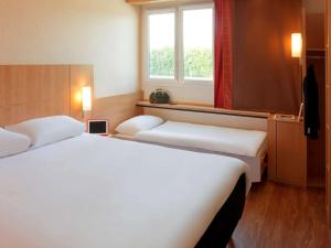 A bed or beds in a room at Ibis Roanne Le Coteau Hotel Restaurant
