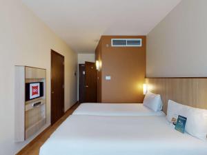 a bedroom with a large white bed and a tv at Ibis Al Barsha in Dubai